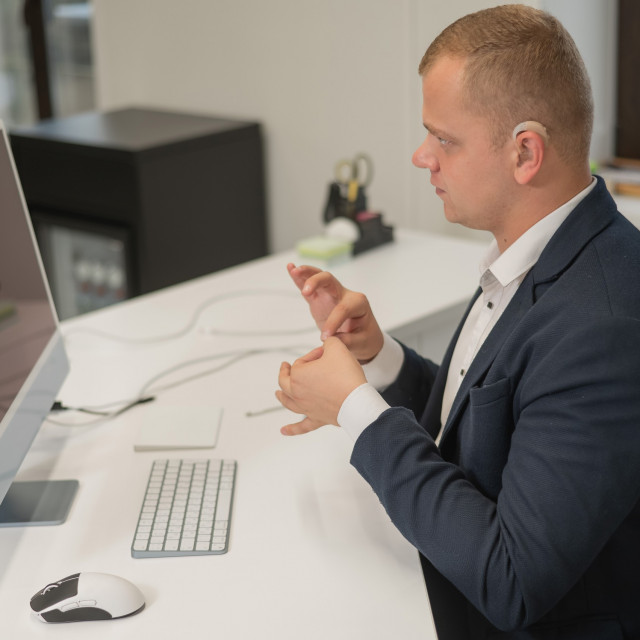 Caucasian deaf man uses sign language for online negotiations.